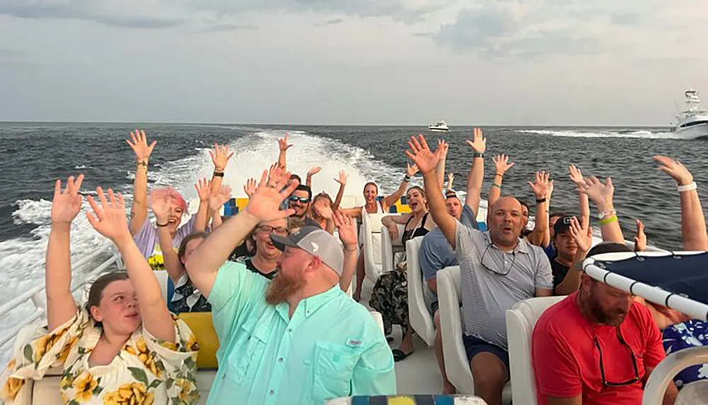 A group of people are joyfully raising their hands in the air while taking a fast boat ride on the sea