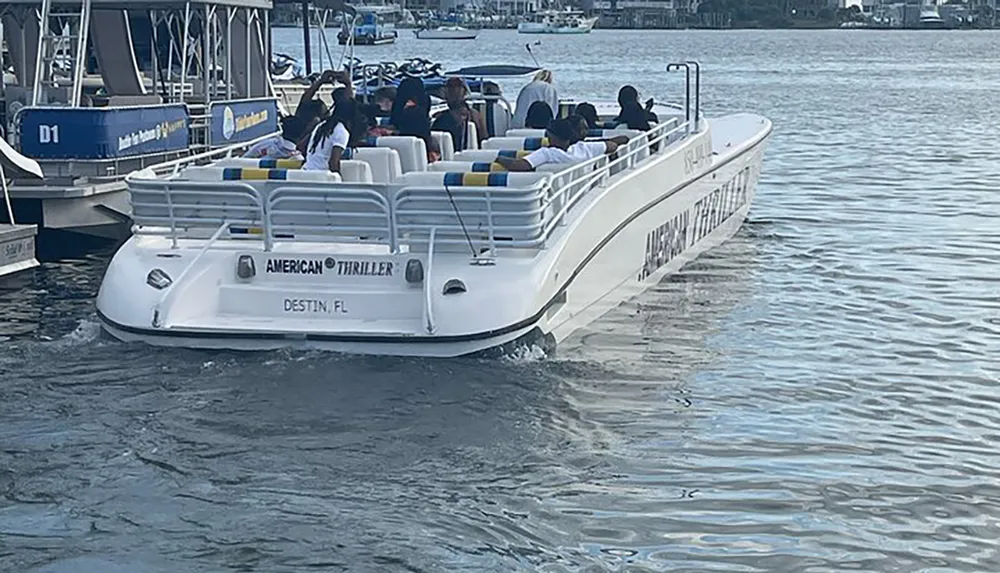 A group of people is seated on a white tour boat named AMERICAN THRILLER in Destin FL as it cruises through the water