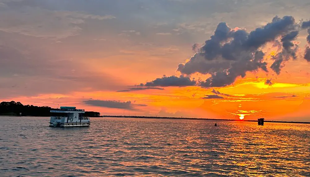 A tranquil scene depicts a boat on calm waters under a stunning sunset sky painted with vibrant hues of orange and yellow