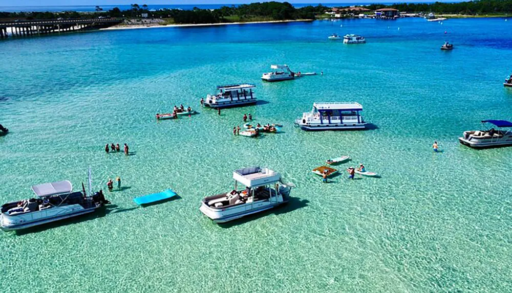 The image shows people enjoying a sunny day on a calm turquoise sea with various boats and floating devices suggesting a popular aquatic recreation spot