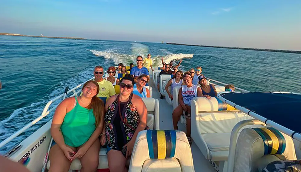 A group of passengers is enjoying a boat ride on a sunny day with some people smiling at the camera