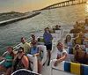 A group of people enjoying a boat ride near a bridge during sunset