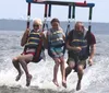 Three people are enjoying a parasailing adventure skimming over the water in a moment of fun