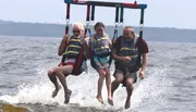 Three people are enjoying a parasailing adventure, skimming over the water in a moment of fun.