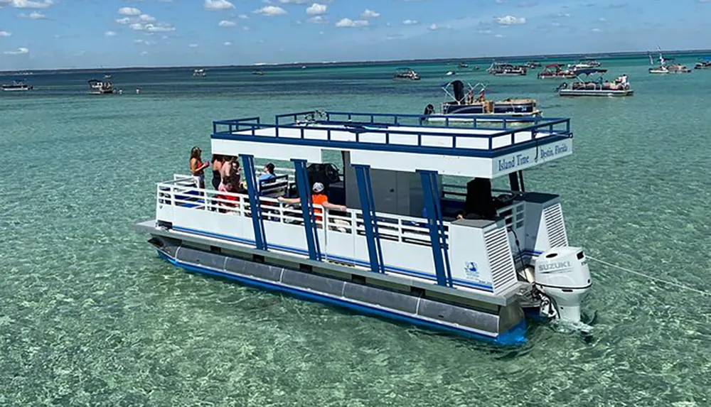 The image shows a group of people on a glass-bottom boat above clear turquoise waters surrounded by other boats and distant land