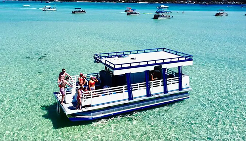 People enjoy the sunny weather on a floating platform boat over clear turquoise waters with other boats in the background