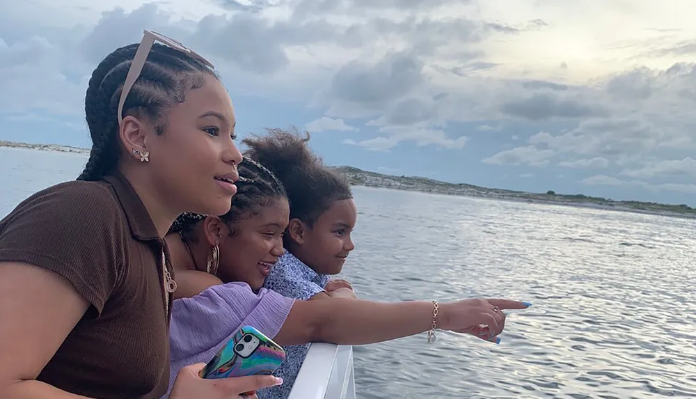 Four individuals appear to be enjoying a boat ride with some pointing towards the ocean expressing excitement or interest in something theyve spotted