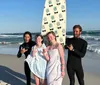 Three smiling people are standing on a sunny beach each with a surfboard ready to enjoy surfing