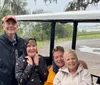 Four smiling people are grouped together in a golf cart seemingly enjoying an outing despite the rainy weather