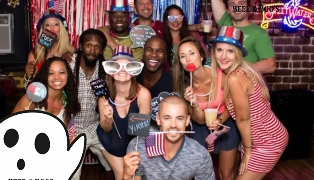 A group of smiling people are posing with festive props and signs giving off a lively party vibe