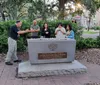 A man is gesturing while speaking to a group of people by a memorial featuring a menorah with the inscription indicating a historical link to James Edward Oglethorpe and the Savannah Jewish Community