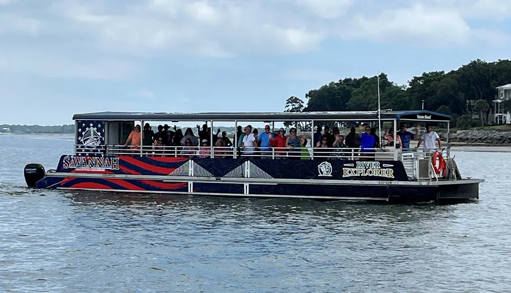 The image shows a group of passengers on a boat named River Explorer with the word Savannah on the side cruising on a body of water