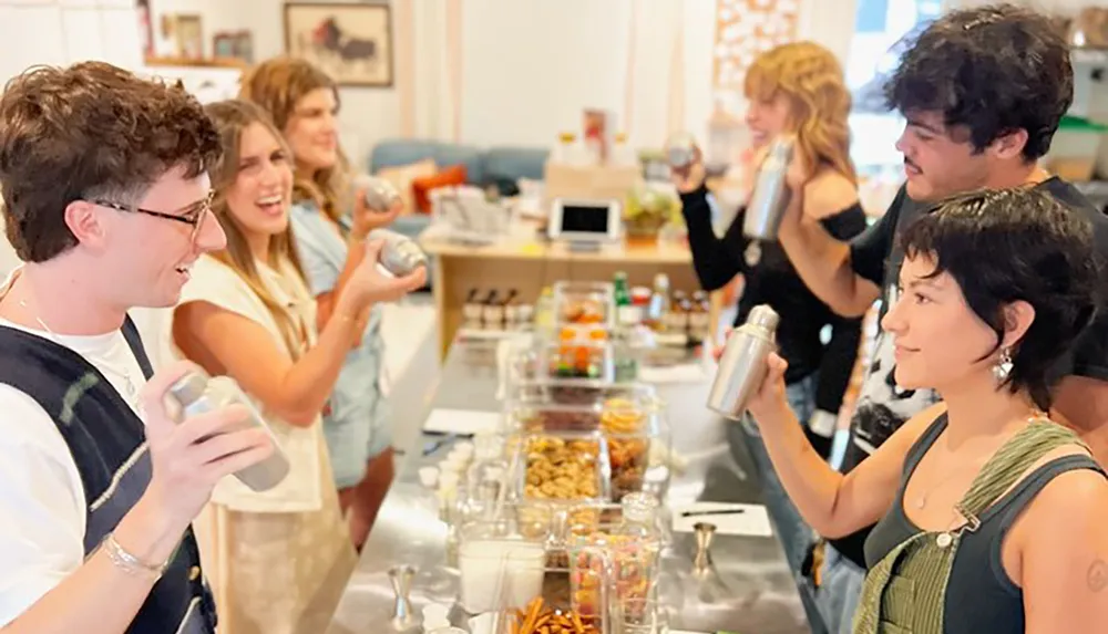 A group of people is happily engaged in what appears to be a cocktail-making class