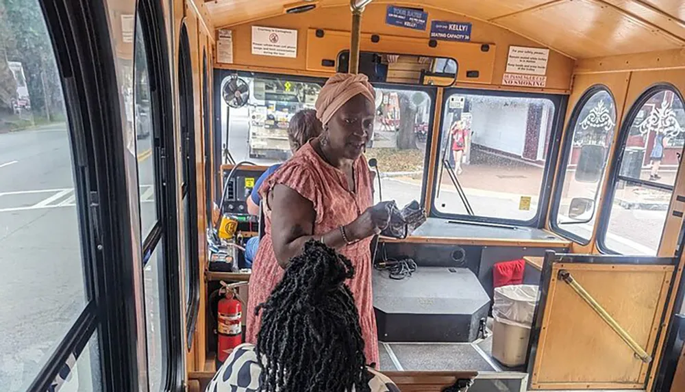 A person is standing inside a trolley bus appearing to be in conversation or interacting with the driver or another passenger