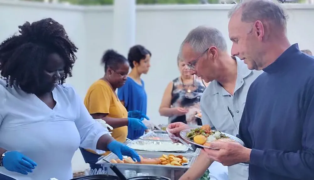 People are serving themselves food from a buffet at an outdoor event