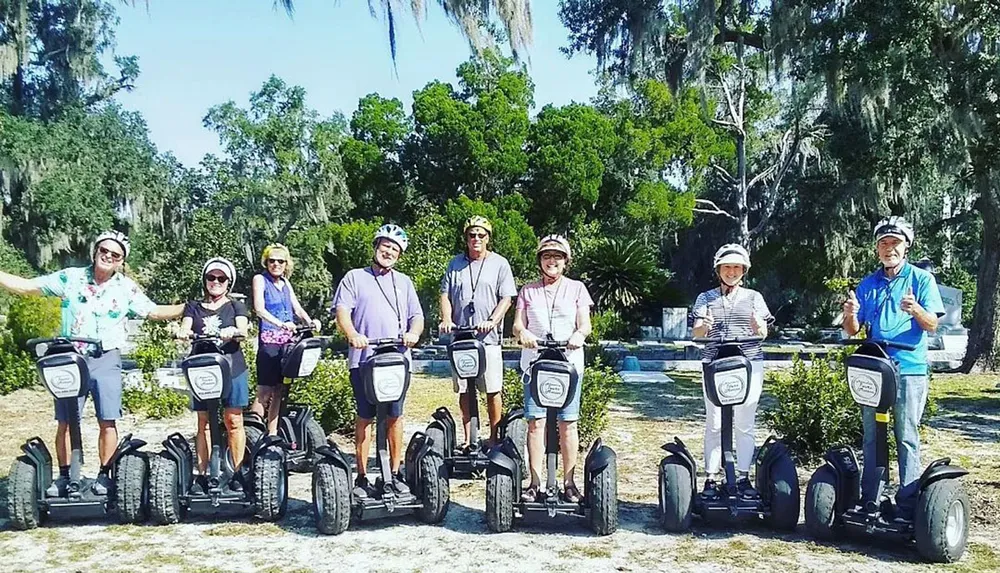 A group of people is posing with their Segways in a park with Spanish moss-draped trees in the background