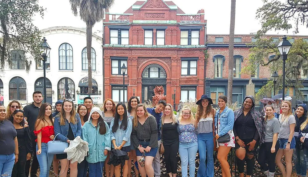 A group of people is posing for a photo in front of an ornate building marked as the Savannah Cotton Exchange