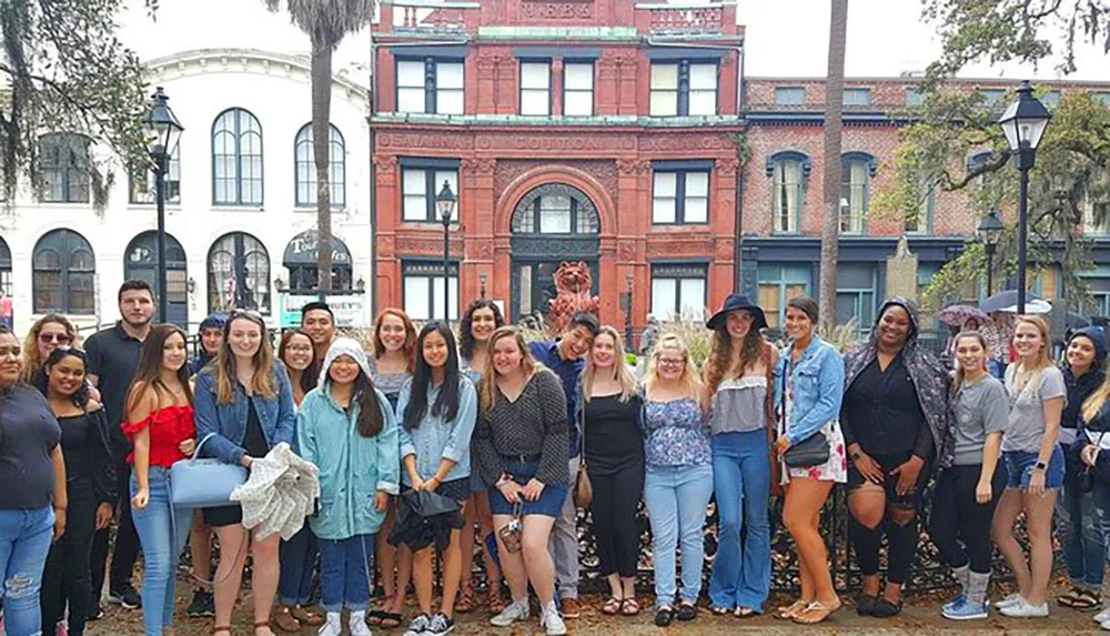 A group of people smiles for a photo in front of a historical building in an urban setting