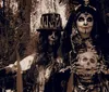 The image features two individuals in elaborate skeletal costumes and face paint resembling skulls with one holding a top hat adorned with small bones and the other cradling a skull set against a dark wooded background