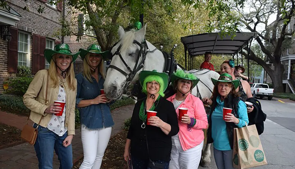 A group of people wearing green hats are posing with a white horse likely during a festive outdoor event