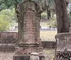 The image shows a peaceful cemetery adorned with statues and Spanish moss-hung trees conveying a serene final resting place