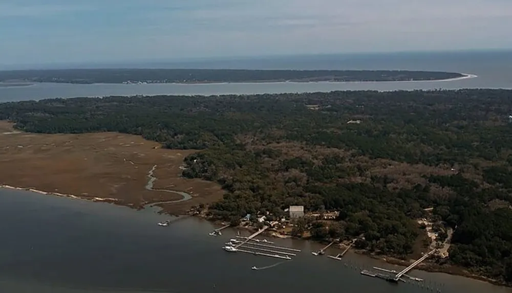 The image shows an aerial view of a coastal area with docks boats and surrounding forested land