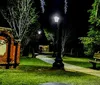 A serene night scene in a park illuminated by street lamps with a winding path a bench and lush greenery