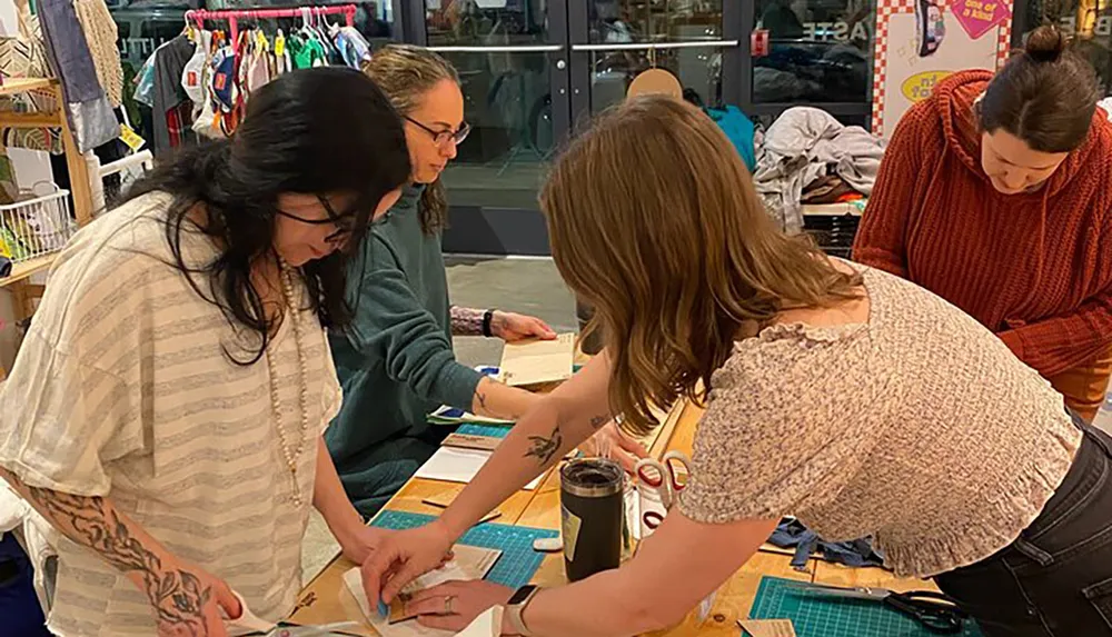 A group of people is engaged in a hands-on activity at a crafting table surrounded by various materials and tools