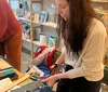 A group of people appears to be engaged in a craft or sewing workshop surrounded by fabric and sewing materials inside a well-lit room