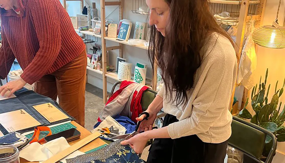 Two individuals appear engaged in crafting activities at a workshop or studio surrounded by various tools and materials