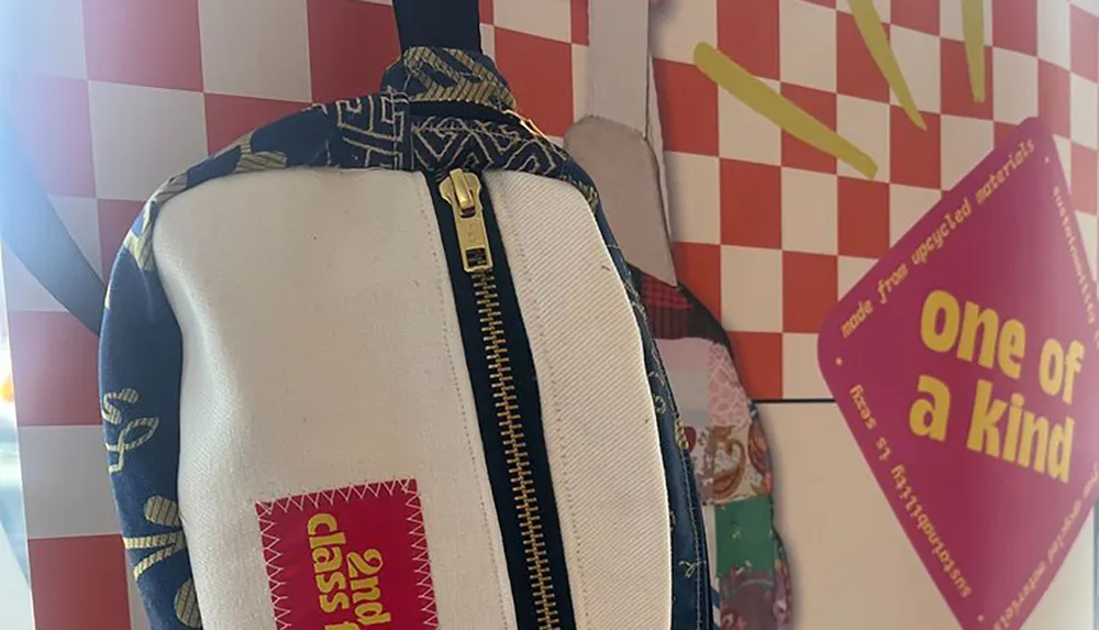 A backpack with a unique patchwork design hangs against a colorful background featuring a one of a kind sign and checkered patterns