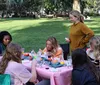 A group of people is enjoying a cheerful outdoor craft activity around a table covered in art supplies