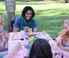 A group of people is enjoying a cheerful outdoor craft activity around a table covered in art supplies