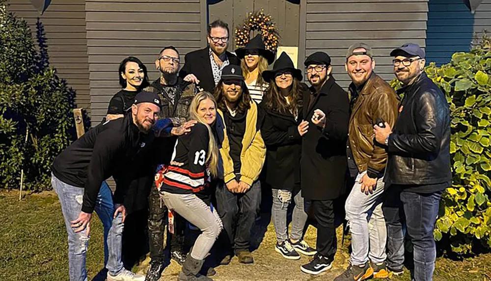 A group of people pose together with smiles in an outdoor setting displaying camaraderie and diverse styles