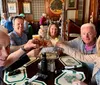 A group of five smiling adults are toasting with drinks at a table inside a restaurant with traditional decor