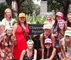 A group of smiling people wearing colorful hats with Bach Party printed on them pose together at Chippewa Square