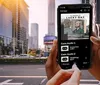 A person is holding a smartphone displaying what appears to be an interactive story or game titled Albions Lucky Day while standing on an urban street with buildings and sunlight in the background