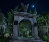 The image displays a charming nocturnal street view adorned with American flags hanging from traditional buildings illuminated by warm streetlights and lined with trees draped in Spanish moss