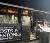 A person in period costume gestures towards a Ghosts  Gravestones tour bus at night