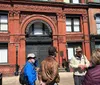 A group of people is on a guided tour outside the historic Savannah Cotton Exchange building