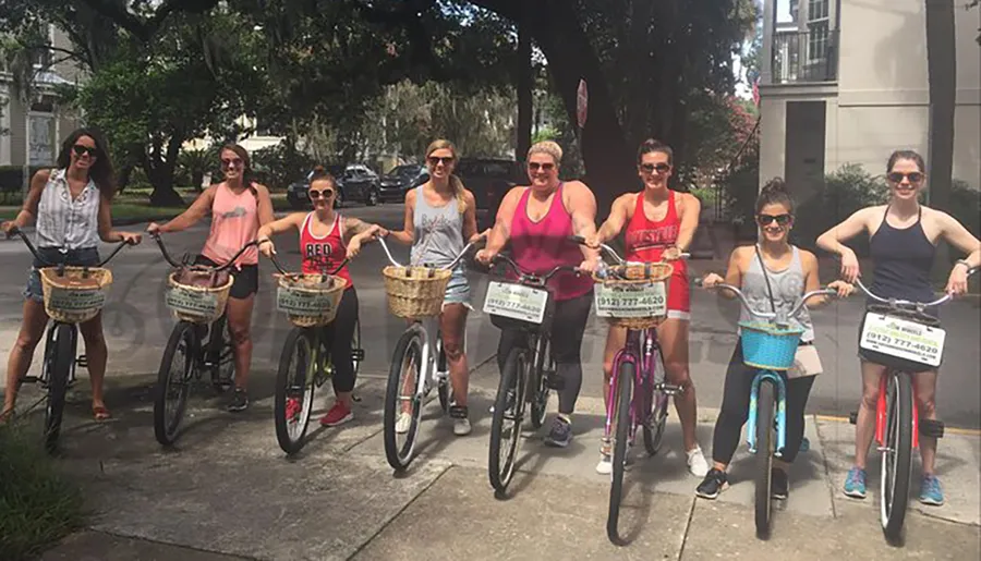 A group of eight women with bicycles are posing for a photo on a sunny day, possibly before or after enjoying a group ride together.