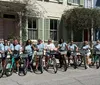 A group of smiling people are standing with rented bicycles in front of a house with a charming facade