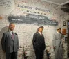 The image shows life-size figures of historical gangster figures Bugs Moran Al Capone and Machine Gun Jack McGurn along with quotes and the American Prohibition Museum Criminal Lineup sign in the background in what appears to be an exhibition related to the Prohibition era