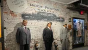 The image shows life-size figures of historical gangster figures Bugs Moran, Al Capone, and Machine Gun Jack McGurn, along with quotes and the 