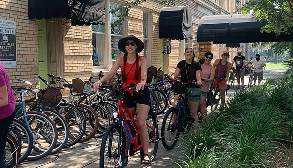 A group of people are smiling and preparing to ride their bicycles on a sunny day in a tree-lined street