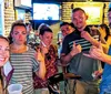 A group of people pose for a photo with some giving a thumbs-up inside what appears to be a casual bar setting