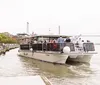 A group of people is enjoying a ride on a riverboat named Ohana that is docked along a city waterfront