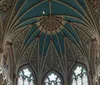 The image shows the intricate vaulted ceiling and stained glass windows of a Gothic-style church interior adorned with colorful patterns and religious iconography