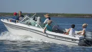 A group of people enjoy a sunny day aboard a white Grady-White motorboat cruising on the water.