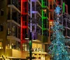 An orange vintage-style trolley adorned with a Christmas wreath travels down a festive cobblestone street at night